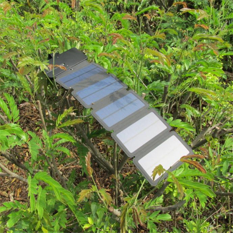 Foldable solar panel attached to a tree branch in a forest setting
